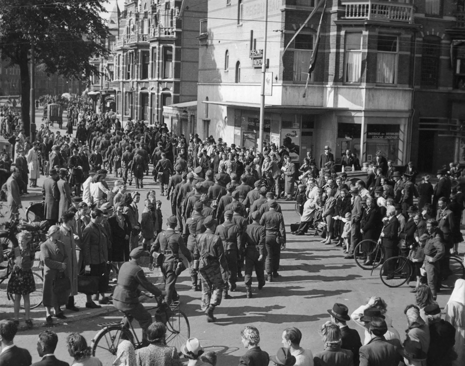 Duitse militairen worden in Den Haag afgevoerd tijdens de bevrijding, de bevolking kijkt toe, 1945. Beeld Nationaal Militair Museum.