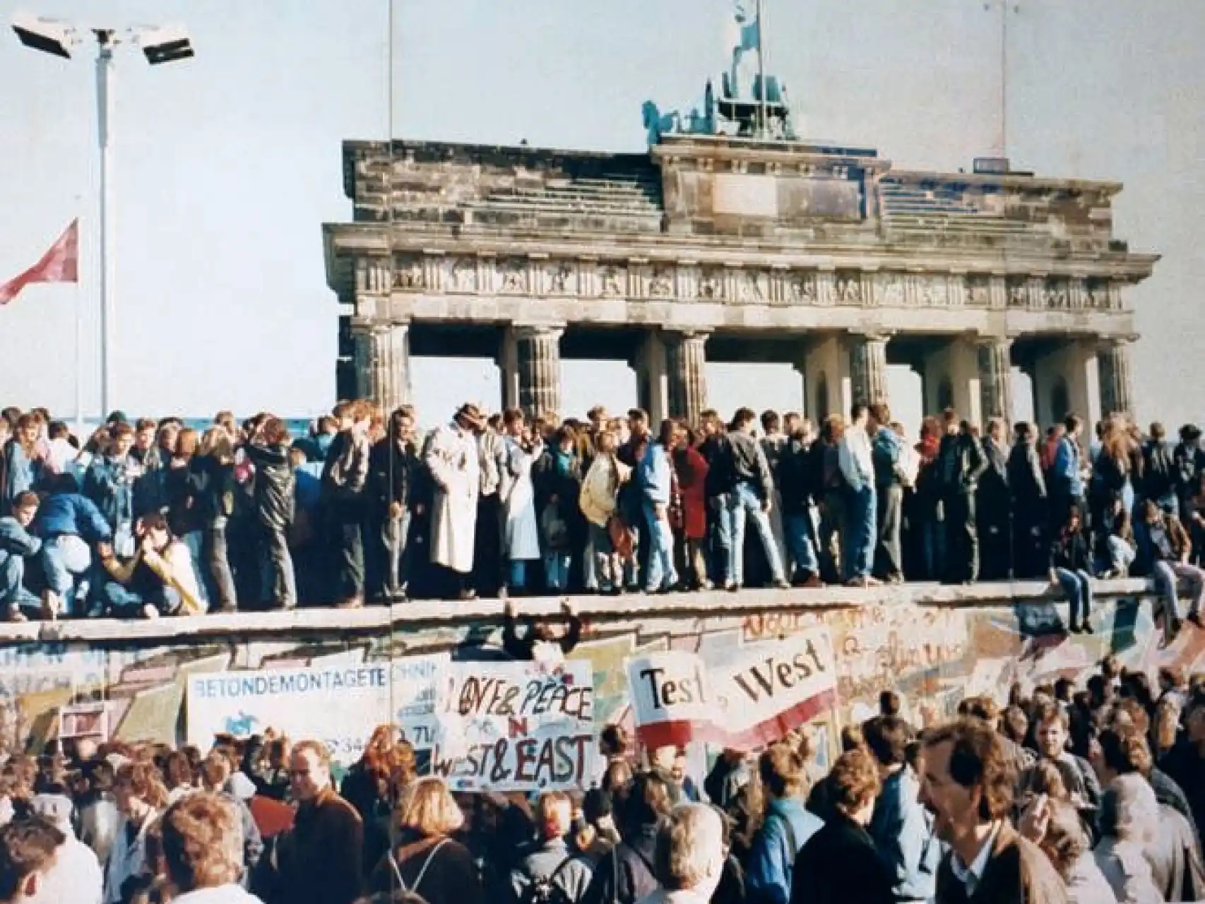 Inwoners uit Oost- en West-Duitsland beklimmen de muur die Berlijn decennialang scheidde, 1989. (Beeld: Senaat Berlijn)